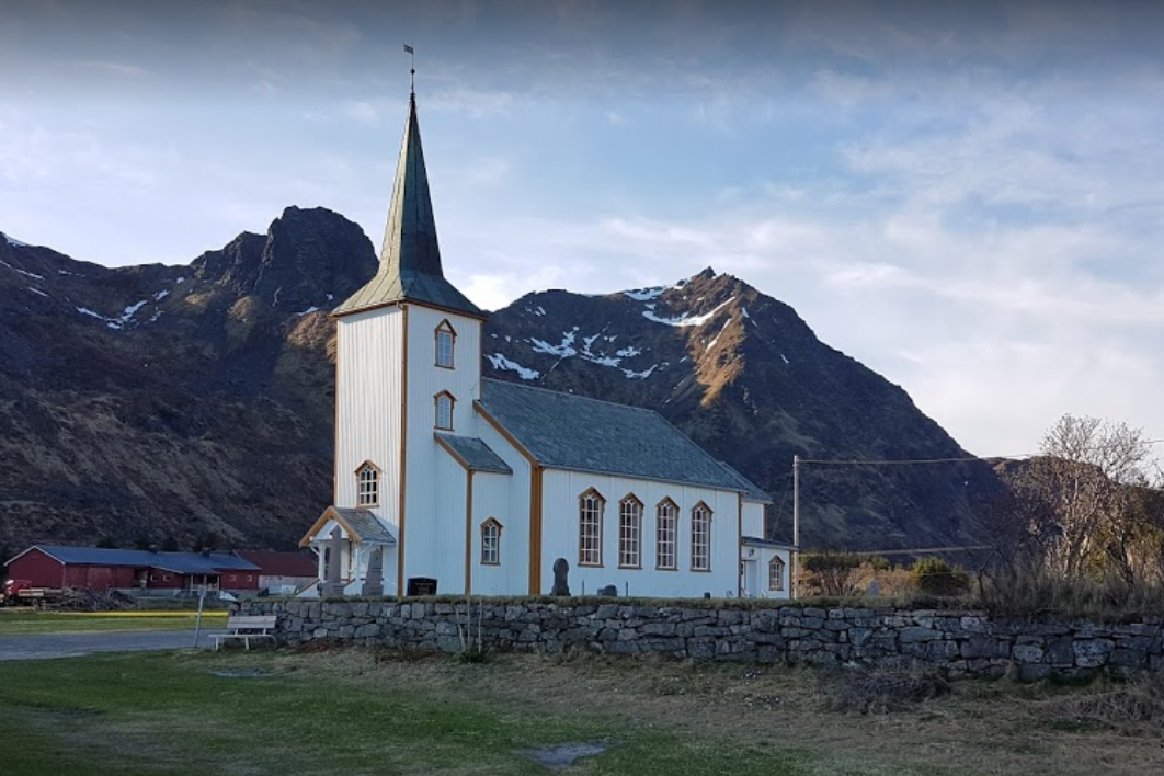 Bilde av Valberg kirke med stenmuren foran og fjell i bakgrunnen